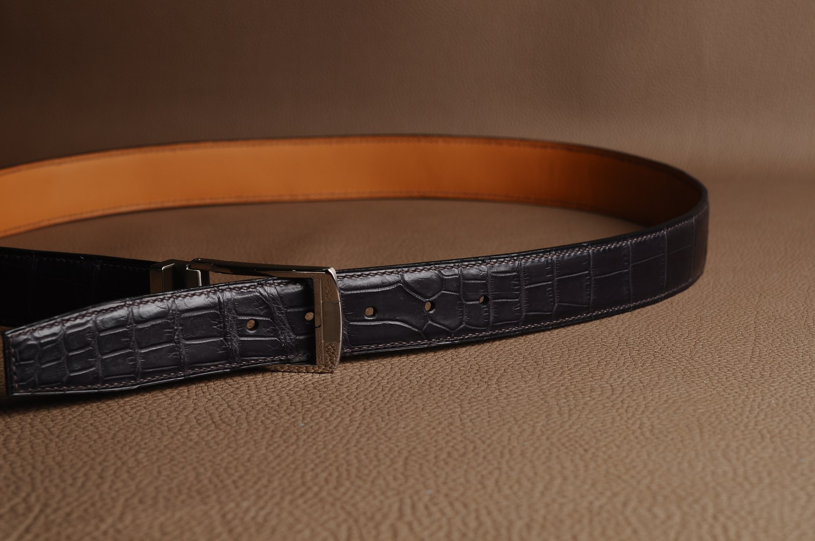 Black crocodile leather belt with a silver buckle and brown lining