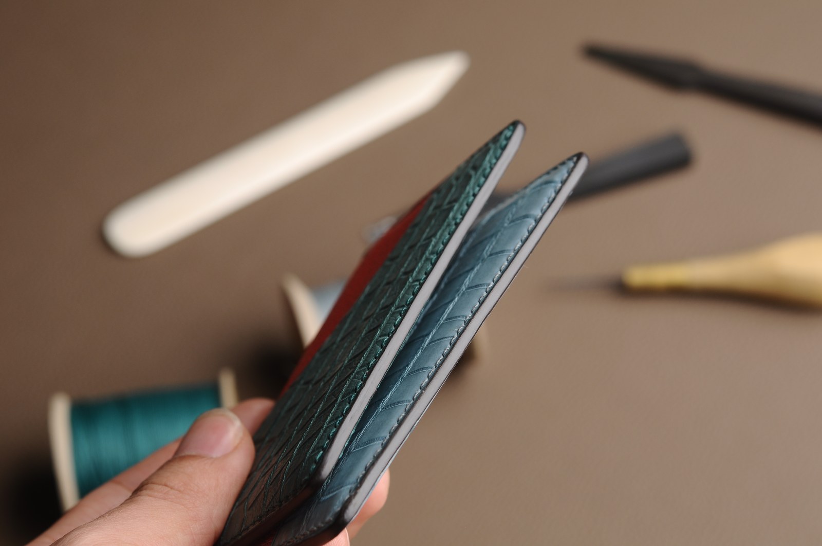 Two light blue card holders held to show their layered edges and thickness